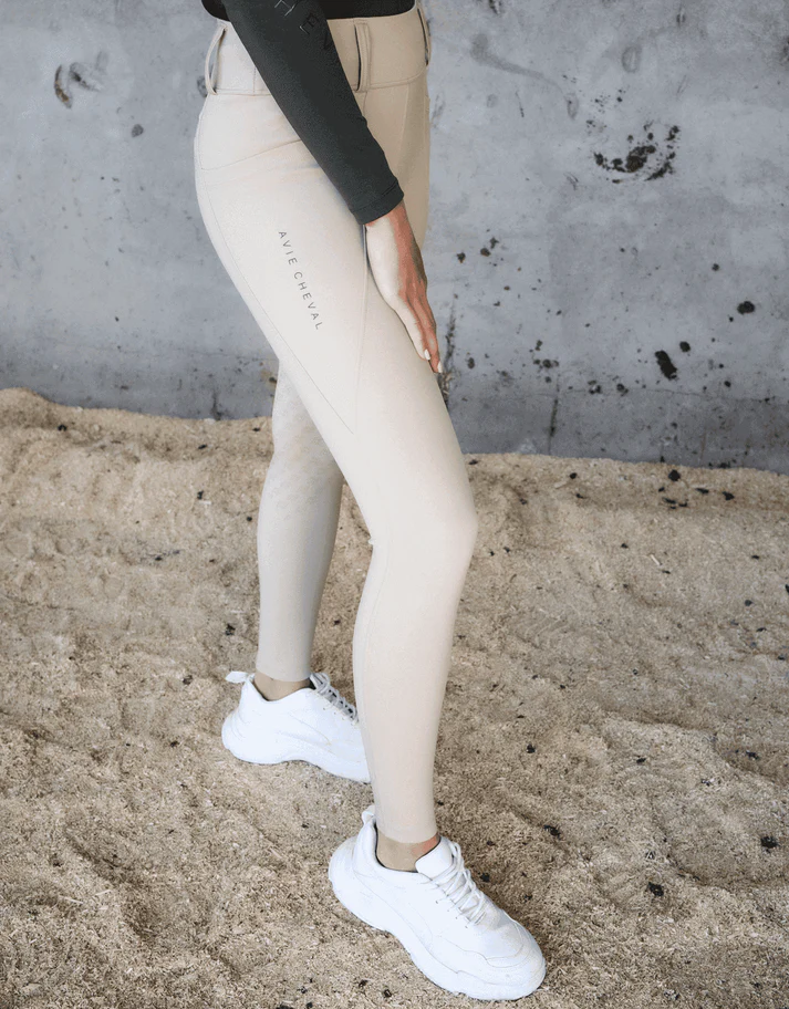 Beige ridleggings med vita sneakers på sand